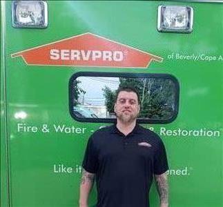 Male employee with blonde hair smiling in front of SERVPRO vehicle .